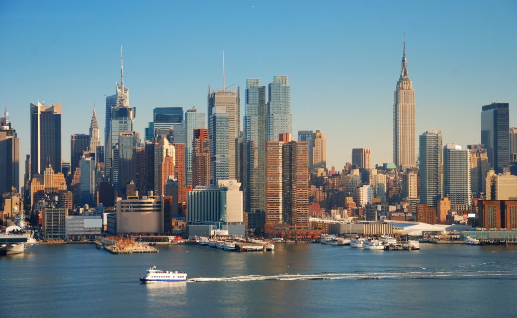 New York City skyline panorama over Hudson river with Empire State Building, boat and skyscraper.